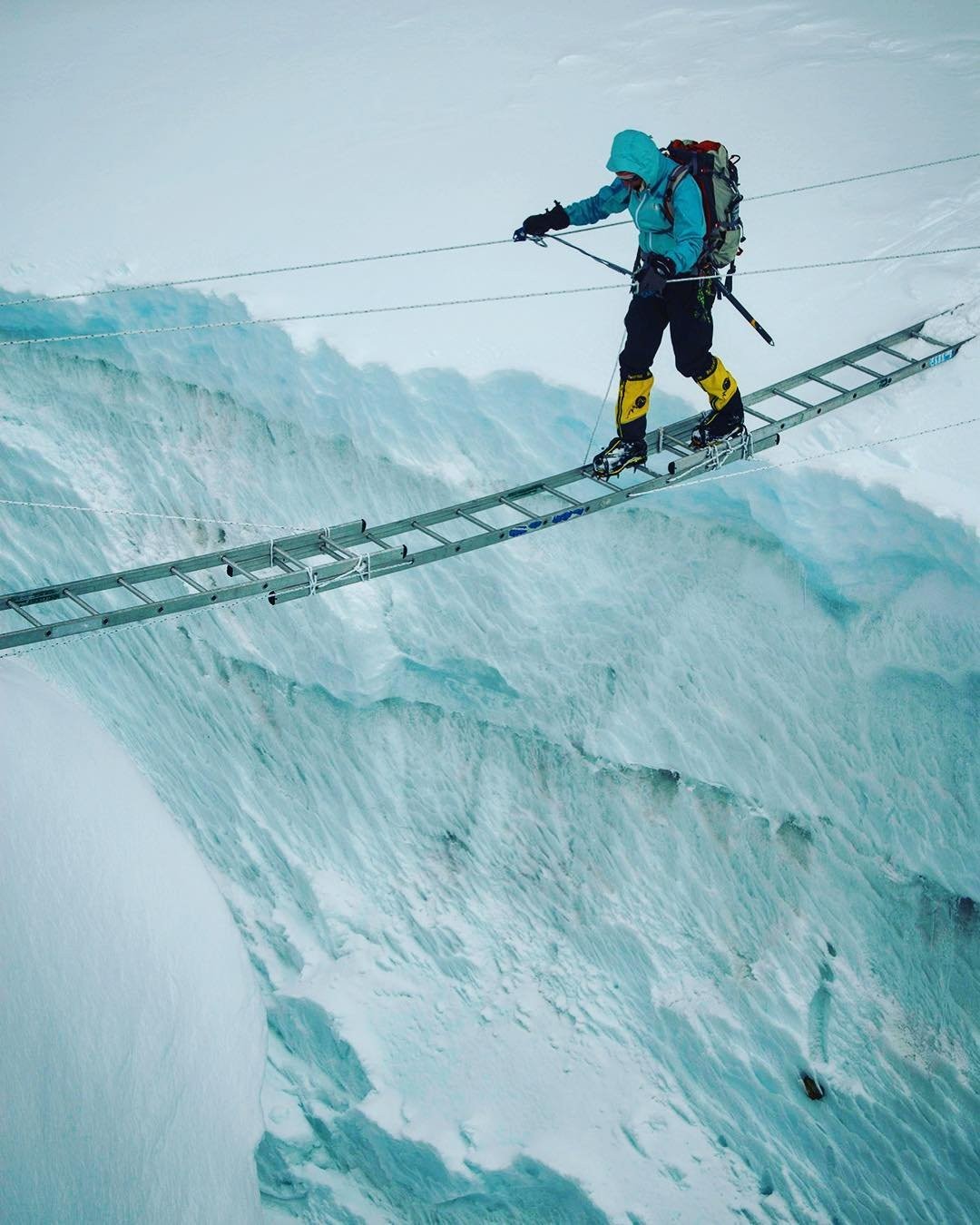 Kit DesLauriers crossing a ladder over a crevasse in the Khumbu Icefall.